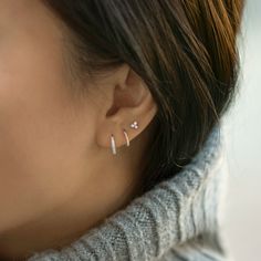 a close up of a woman's ear with two small diamond earrings on it