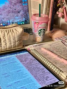 a laptop computer sitting on top of a desk next to a cup of coffee and notebook