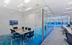 an empty conference room with glass walls and blue flooring is pictured in this image