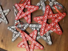 christmas ornaments made out of wood and decorated with white and red shapes on a wooden table