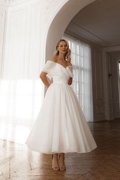 a woman in a white dress posing for the camera with her hands on her hips