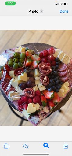 an image of a platter of fruit and cheeses on a wooden table top