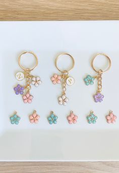 four keychains with flowers on them sitting on a white plate next to each other