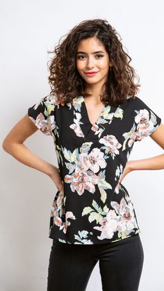 a woman standing with her hands on her hips wearing a black and white floral dress