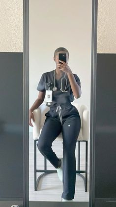 a woman sitting in a chair taking a selfie with her cell phone and stethoscope