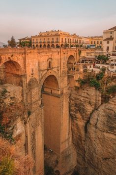 an old bridge built into the side of a cliff with buildings on top and below