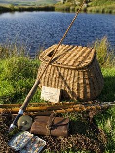 an old fishing pole is sitting in the grass next to a basket and other items