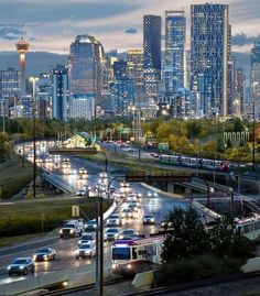 the city skyline is lit up at night as traffic moves down the street in front of it