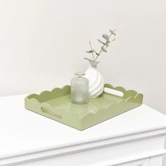 a white vase sitting on top of a green tray