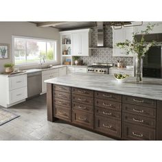 a large kitchen with white cabinets and marble counter tops, along with wooden flooring