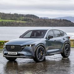 a grey mazda cx - 5 parked in front of a lake