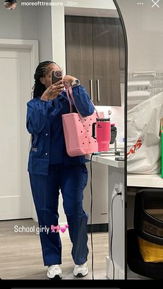 a woman taking a selfie in front of a mirror while holding a pink purse