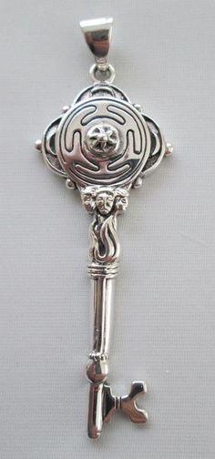 a silver key with a skeleton on it is hanging from a chain that's attached to a wall