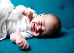 a smiling baby laying on top of a blue couch