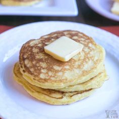 three pancakes with butter on top are sitting on a white plate next to another plate