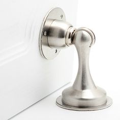 a close up of a metal door handle on a white door with a white wall in the background