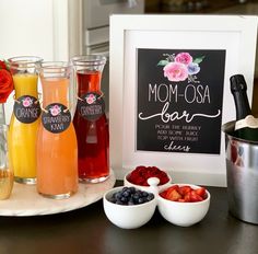 a table topped with drinks and fruit next to a chalkboard sign that says mom - osa bar