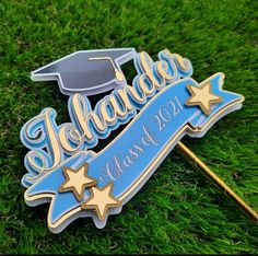 a blue and gold graduation pin sitting on top of green grass