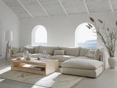 a living room filled with lots of furniture next to large windows and an ocean view