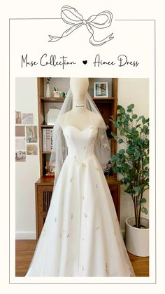 a white wedding dress on display in front of a bookcase and potted plant