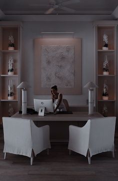 a woman sitting at a desk in front of a laptop computer