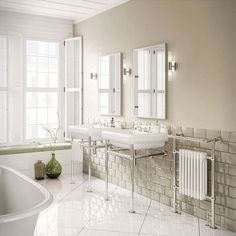 a bathroom with two sinks, a bathtub and three mirrors