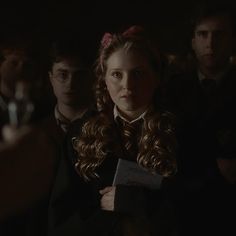 a group of young people standing next to each other in a dark room with one girl holding a book