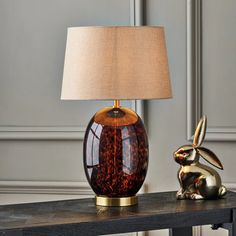 a table with a lamp on it and a rabbit figurine next to it