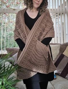 a woman standing in front of a couch wearing a brown knitted sweater and black leggings