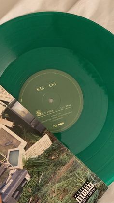 a green vinyl record sitting on top of a white table next to an album cover