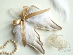 a white feather with gold ribbon and pearls