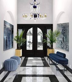 an elegant entry way with black and white tile flooring, chandelier and blue chairs