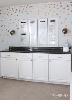 a kitchen with white cabinets and gold dots on the wall