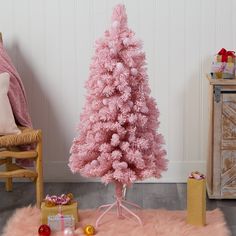 a pink christmas tree in a living room with presents on the floor and other decorations