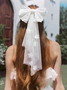 the back of a woman's head wearing a white veil with flowers on it