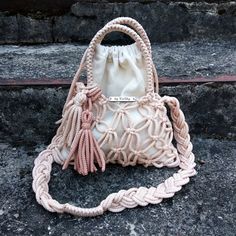 a white purse sitting on top of a cement floor next to some steps with a handbag hanging from it