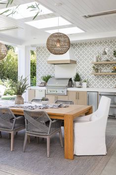 a dining room table with chairs and an oven in the back ground, surrounded by plants