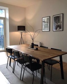 a dining room table with four chairs and a lamp on the wall next to it