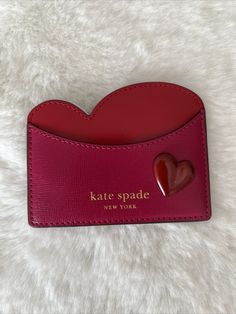 a red card case with a heart on the front that says kate spade new york