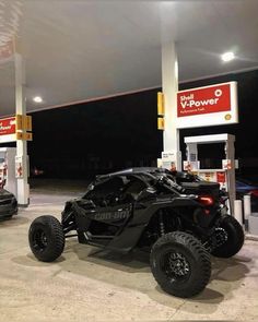 a black can - am spyder parked in front of a gas station at night