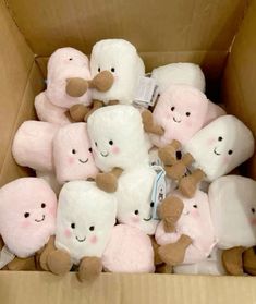 a cardboard box filled with lots of white and pink stuffed animals in different shapes and sizes