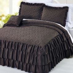 a bed with brown ruffled bedspread and pillowcases in front of a window