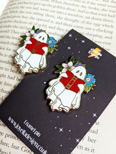 two ghost pin badges sitting on top of an open book