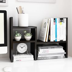 a computer monitor sitting on top of a desk next to a clock and other office supplies