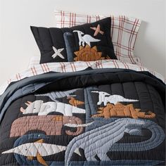 an image of a bed with dinosaurs and birds on the comforter in this bedroom