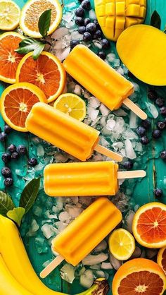 popsicles with oranges, lemons and blueberries are on a green platter