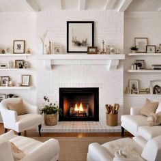 a living room filled with white furniture and a fire place in the middle of it