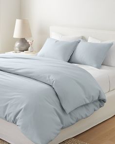 a bed with blue sheets and pillows in a bedroom