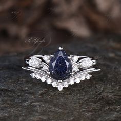 a blue diamond ring sitting on top of a black rock with white diamonds around it