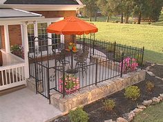 a patio with an umbrella over it and flowers on the ground in front of it